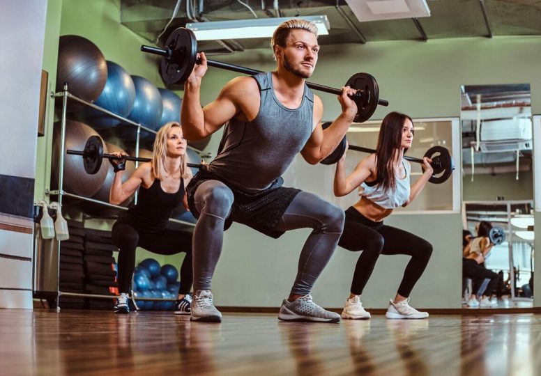 group-of-people-exercising-with-barbell-doing-squa-JUWGZQJ
